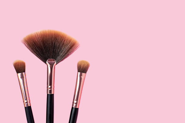 A set of professional makeup brushes on a pink background. Stylish makeup artist tools in black and rose gold color. Concept for womens cosmetics, beauty concept, skincare. Copy space for text. - Foto, immagini