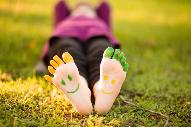 Child having fun in spring park outdoors. Smiley on feet.  - Photo, Image