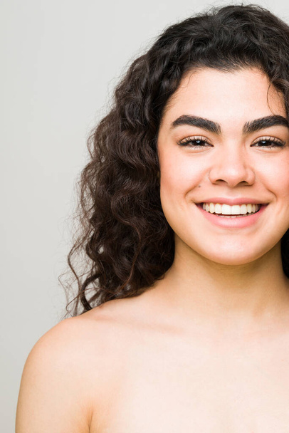 Счастливая 20-летняя латиноамериканка улыбается. Обрезанное фото молодой женщины и модели красоты со здоровой кожей и обнаженными плечами   - Фото, изображение