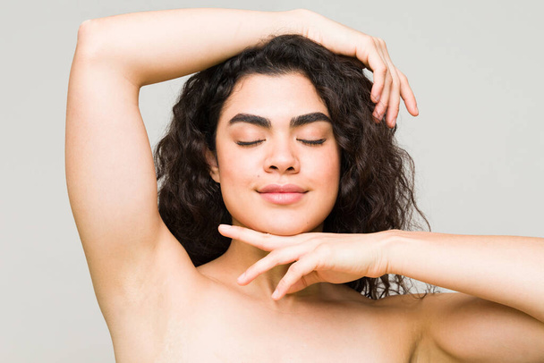 Mujer joven hispana sintiéndose feliz y relajada después de recibir un tratamiento dermatológico. Modelo de belleza en el spa con la piel brillante  - Foto, Imagen