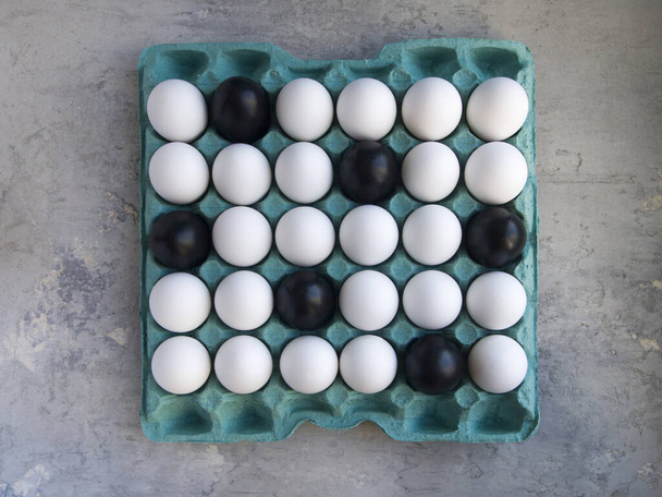 Csirketojások nagy csomagolása. A legtöbb fehér, de vannak feketére festett tojások. Szokatlan színek egy hagyományos nyaraláshoz. Húsvéti ötletek. - Fotó, kép