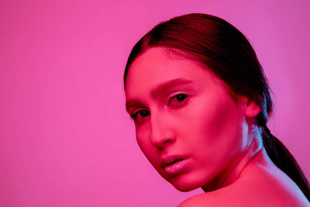 Beautiful east woman portrait isolated on pink studio background in neon light, monochrome - Zdjęcie, obraz