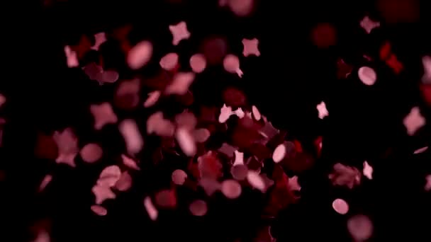 Punainen konfetti putoaa hidastettuna mustaan kuiluun, studiokuva. - Materiaali, video