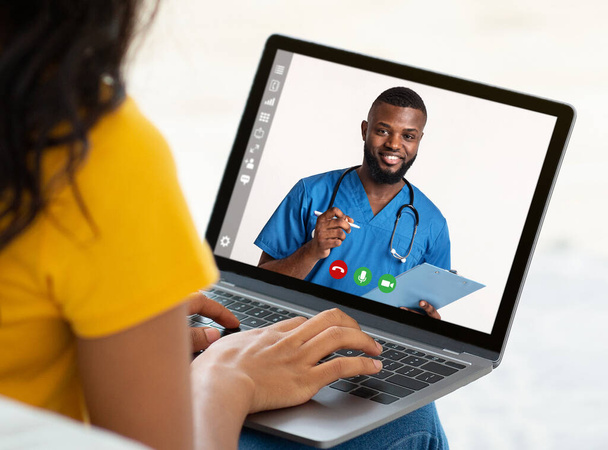 Здравоохранение. Молодая женщина проводит телеконференцию с врачом на ноутбуке, получает профессиональную медицинскую помощь - Фото, изображение