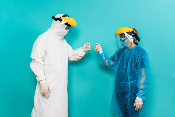 Foto d'archivio degli operatori sanitari che indossano una tuta protettiva per la merluzza19 guardandosi l'un l'altro sullo sfondo blu. - Foto, immagini