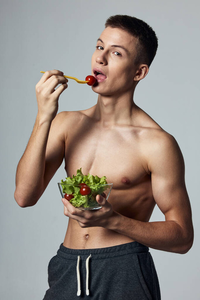 atletico ragazzo con busto muscolare mangiare insalata dieta cibo sano - Foto, immagini