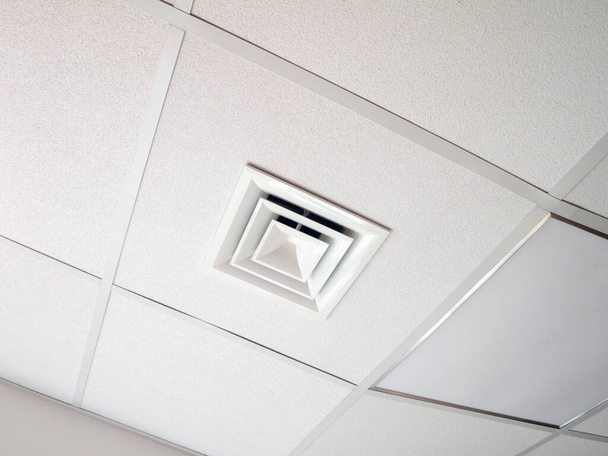 Hood on a false ceiling in an office room. Part of a split system that provides ventilation, air conditioning and heating. - Photo, Image