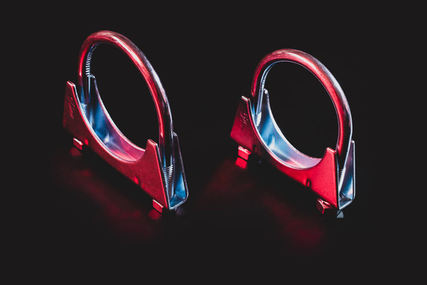 Due morsetti per tubo di scarico isolati su nero in moderna illuminazione rossa e blu drammatica. - Foto, immagini
