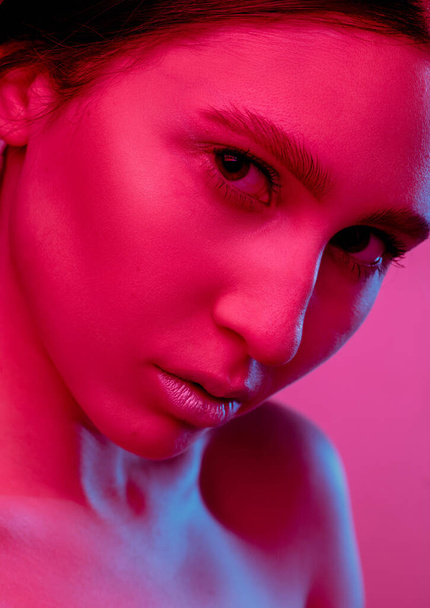 Beautiful east woman portrait isolated on pink studio background in neon light, monochrome - Foto, afbeelding