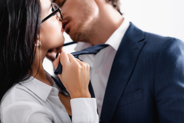 partial view of passionate couple of businesspeople kissing in office, blurred background - Fotografie, Obrázek