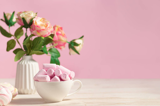 Holiday festive romantic table decorated with flowers and a cup with poink marshmallows - Foto, Imagem