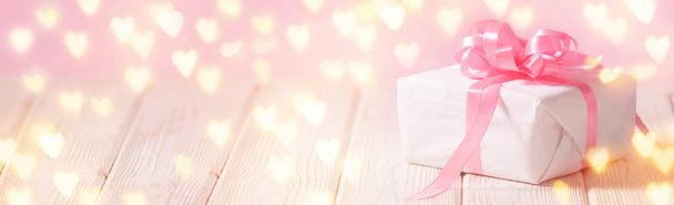 Banner with white box with pink ribbon on the light wooden table with copy space for text - Foto, Bild