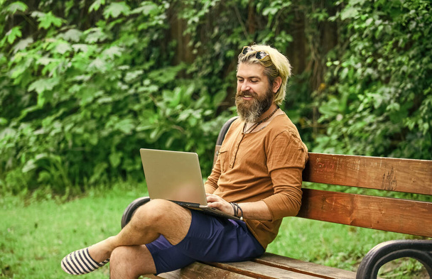 Fresh air. Mobile internet. You can work anywhere. Agile business. Bearded guy sit on bench in park nature background. Work and relax. Online shopping. Working online. Hipster inspired work in park - Valokuva, kuva