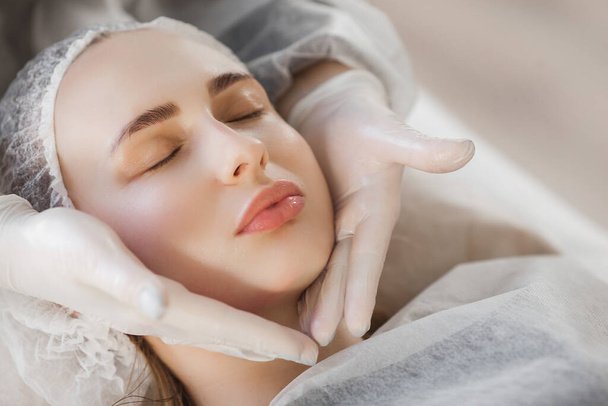Cosmetoligist maakt gezichtsbehandeling. Gezichtsheffen massage. Huidverzorging - Foto, afbeelding