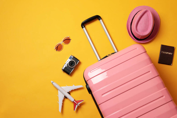 Flat lay composition with suitcase and travel accessories on yellow background. Summer vacation - Foto, imagen