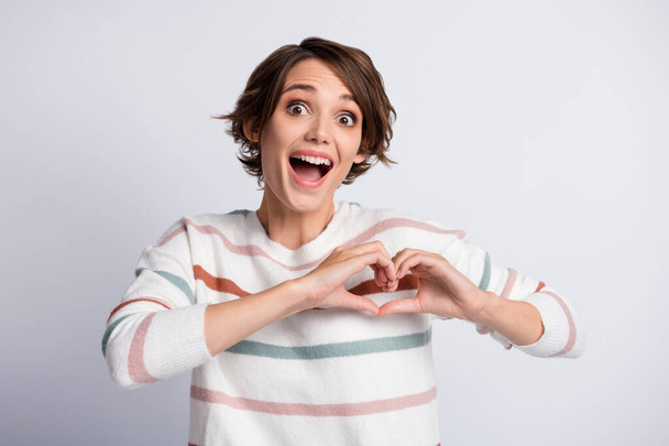 Photo of impressed young lady wear striped sweater open mouth showing fingers heart isolated grey color background - Φωτογραφία, εικόνα