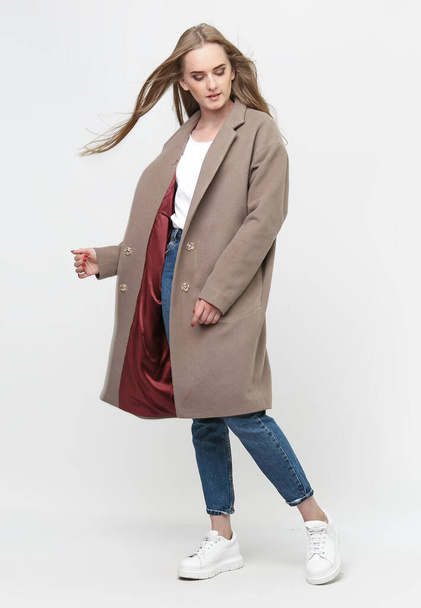 beautiful model posing in a brown long coat on a white background. studio shot. Clothing advertising concept. - Foto, Bild