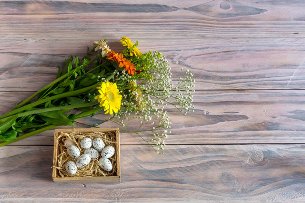 La composición de Pascua. Huevos y gerberas multicolores sobre fondo de madera. - Foto, Imagen