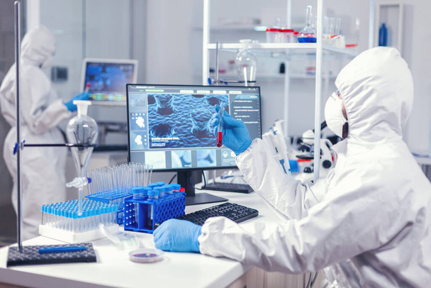 Scientist checking tube with blood analysis dressed in ppe - Zdjęcie, obraz
