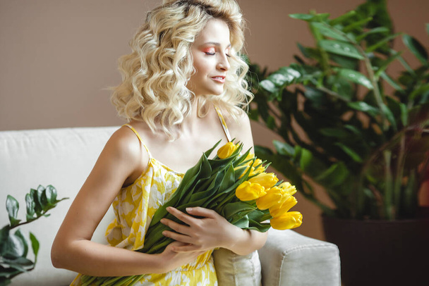 Beautiful blond woman with bouquet of yellow tulips - Foto, imagen
