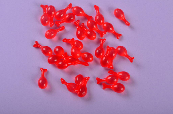 Farmaseuttiset pehmeät punaiset gelatiinikapselit violetilla pohjalla. Polypeptidi Kapseli Kaviaari Essence Liquid Laimennukset Fine Lines Kirkastaminen Kosteuttava Valkaisuaine Essenssi Ihonhoito - Valokuva, kuva