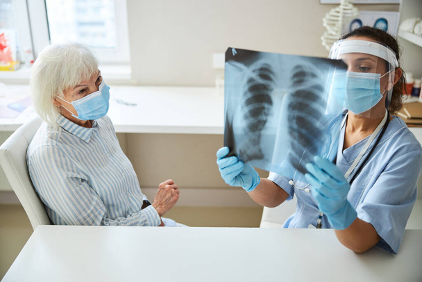 Female doctor studying an x-ray diagram with patient - Фото, изображение