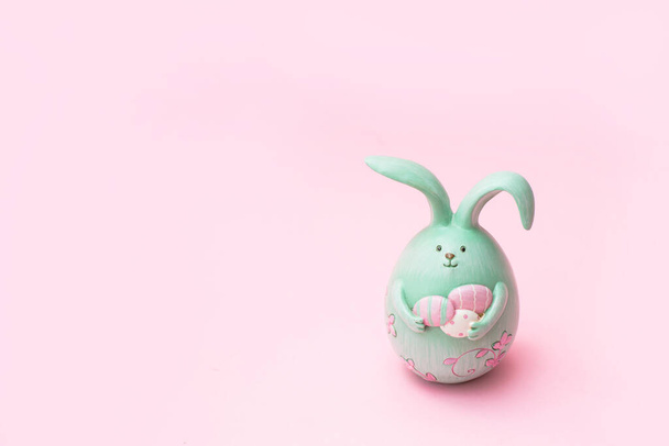 Lindo conejito creativo de Pascua foto sosteniendo huevos sobre fondo rosa con espacio de copia - Foto, imagen
