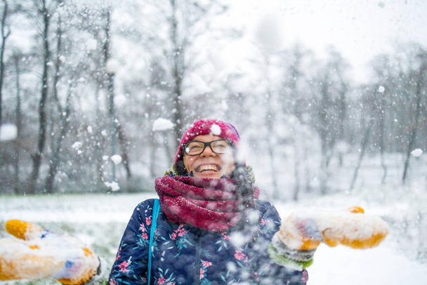 Frau wirft Schnee in die Luft und genießt einen kalten Wintertag - Foto, Bild