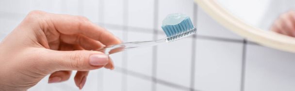 歯磨き粉を手に歯ブラシを持っている女性の切り取りビューバナー - 写真・画像