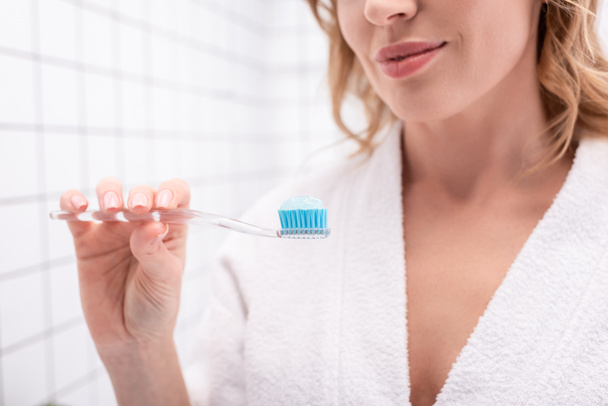 歯磨き粉で歯ブラシを持っている陽気な女性の部分的なビュー  - 写真・画像