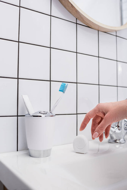 cropped view of woman reaching container with dental floss in bathroom  - Photo, image