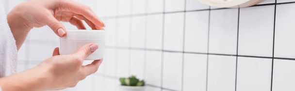 cropped view of woman holding jar with face cream in bathroom, banner - Фото, зображення