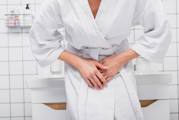 Teilbild einer Frau im Bademantel, die im Badezimmer unter Bauchschmerzen leidet - Foto, Bild