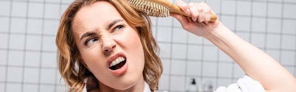 δυσαρεστημένη γυναίκα βούρτσισμα μαλλιών στο μπάνιο, πανό - Φωτογραφία, εικόνα