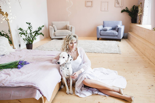Beautiful blond woman with embracing dog - 写真・画像