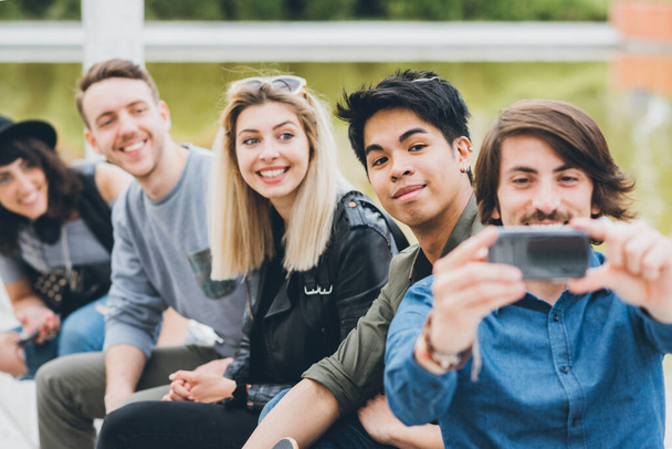 Grupa wieloetnicznych przyjaciół na świeżym powietrzu dobrze się bawiąc i robiąc selfie za pomocą smartfona odkryty w mieście  - Zdjęcie, obraz