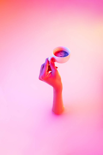 Close up female hand gesturing from the milk bath with soft glowing in neon light - 写真・画像