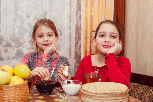 Két 8 és 10 éves lány palacsintával az asztalnál. - Fotó, kép