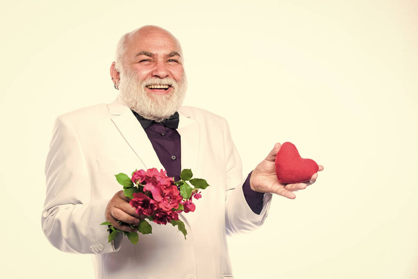 Правдиве кохання. щасливий зрілий чоловік тримає квіти і серце. любов і романтика. Охорона здоров'я. проблеми з серцем. бородатий бізнесмен. серцева недостатність. ювілей і день валентинки. трансплантація донора
 - Фото, зображення