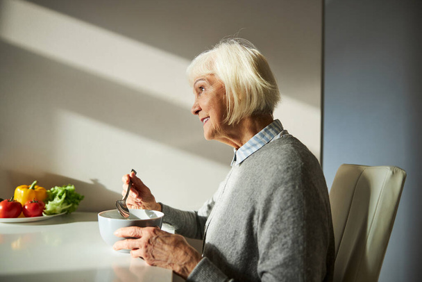Happy female pensioner enjoying her morning meal - 写真・画像