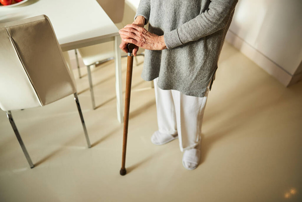 Woman in pants and a tunic using a cane - Foto, imagen