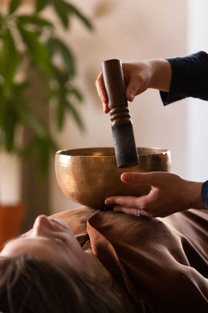 Donna che fa massaggi rilassanti, meditazione, terapia del suono con ciotole tibetane. Alleviare lo stress. Concentrazione selettiva. Vista dal basso.  - Foto, immagini