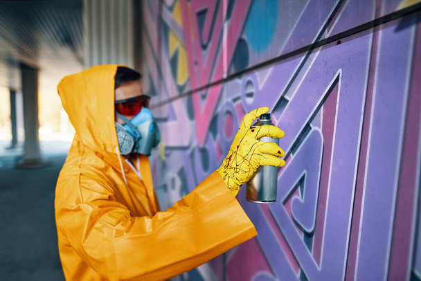 Street artist painting colorful graffiti on wall - Foto, afbeelding