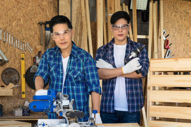 Dos carpinteros trabajan en una fábrica de madera. El carpintero está dibujando la madera. Hombre concentrado cortando madera. - Foto, imagen
