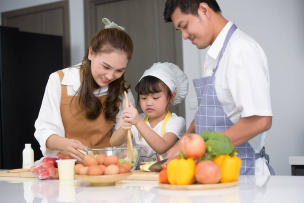 アジアの家族は、現代の家庭のキッチンルームで自家製のサラダ料理を一緒に調理してお楽しみください。家族で一緒に活動を作成します。センターの子供たちにソフトフォーカス. - 写真・画像