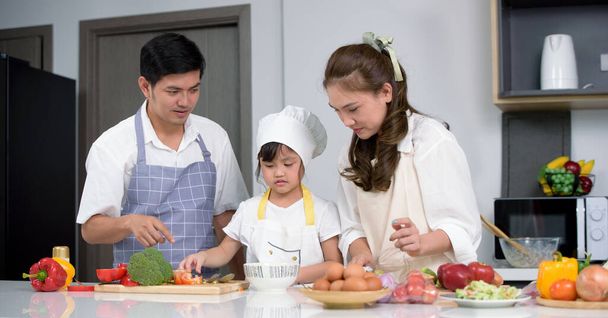 Asyalı aileler, modern evdeki mutfak odasında ev yapımı salata yemeklerinden hoşlanırlar. Aile içinde aktiviteler oluşturun. Merkezdeki çocuklara odaklanma. - Fotoğraf, Görsel