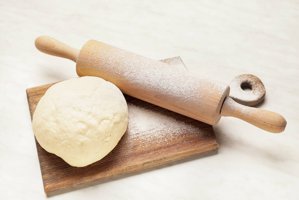 Fresh dough and rolling pin on light background - Photo, Image
