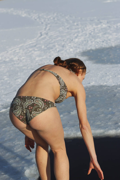 epiphany feast. Girl in swimsuit bathing in ice-hole hardening, recovery, a young woman plunges into the icy water of a lake, Ukraine, January - Valokuva, kuva