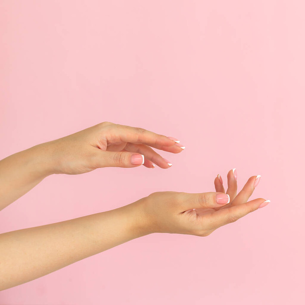 Krása a péče o pleť - mladé ženské ruce s francouzskou manikúrou po lázeňské léčbě na světle růžovém pozadí, kopírovací prostor - Fotografie, Obrázek
