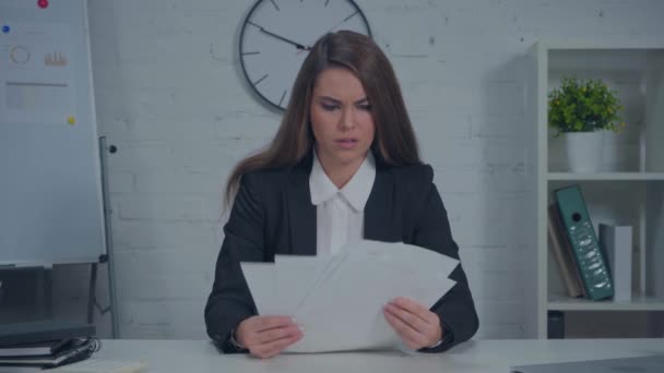 niezadowolona bizneswoman patrząc na dokumenty w biurze - Materiał filmowy, wideo